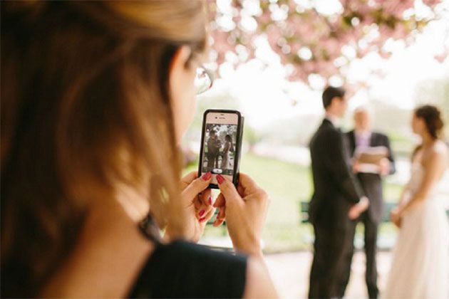 Guest taking photo of bride and groom on phone