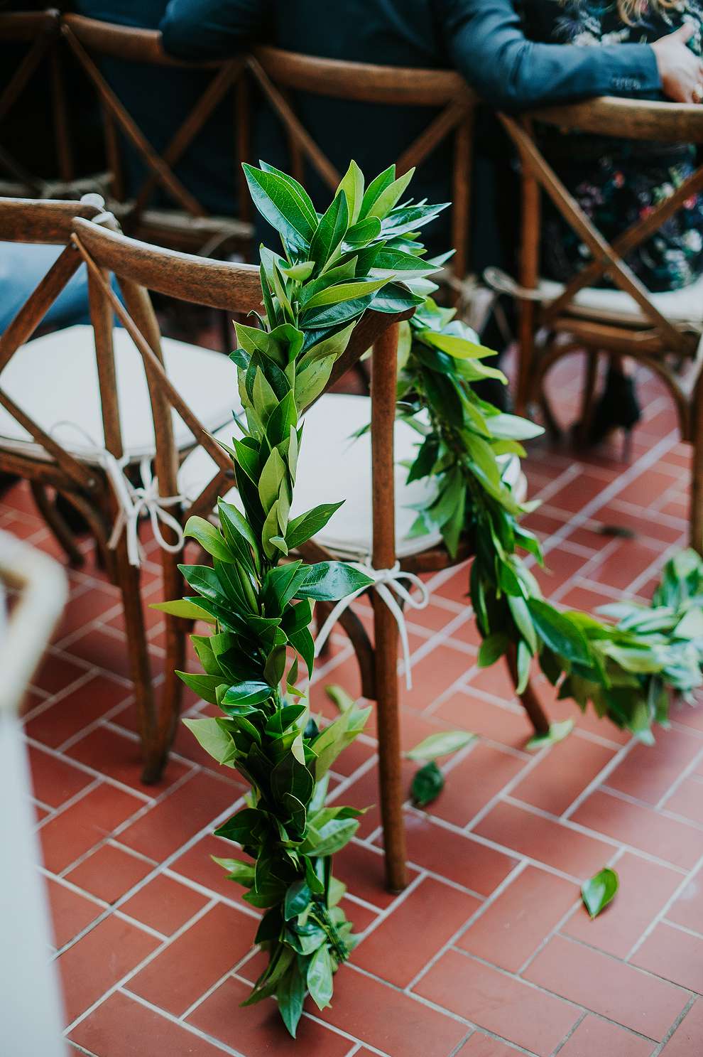 Greenery on ceremony chairs with a red brick floor