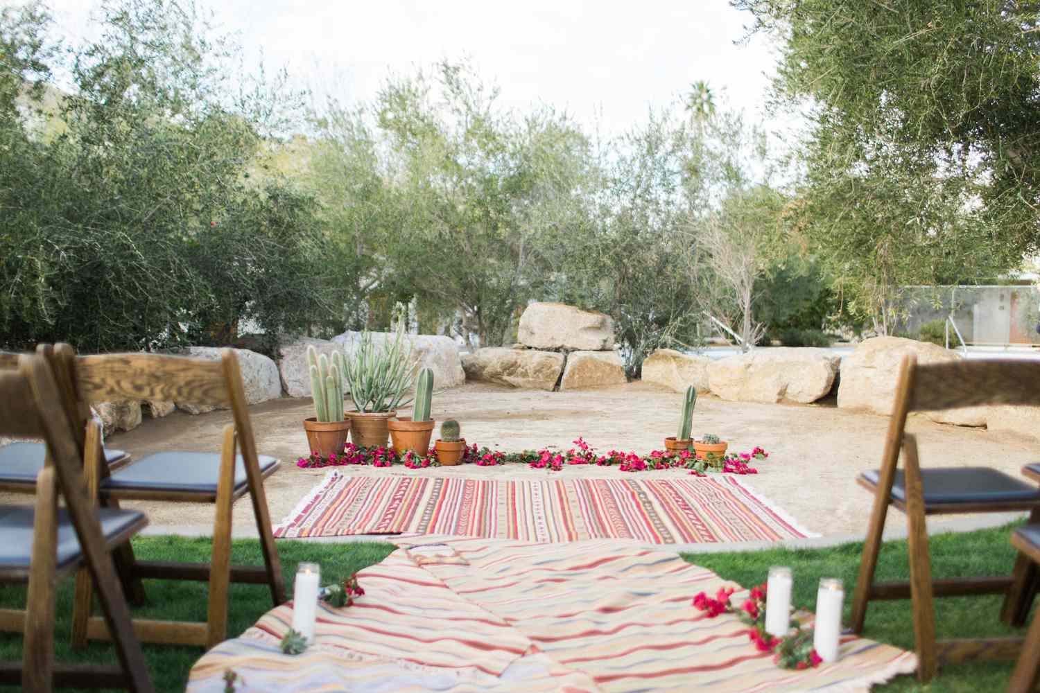 Wedding ceremony with rugs down the aisle and a rug with flowers and cacti at the end