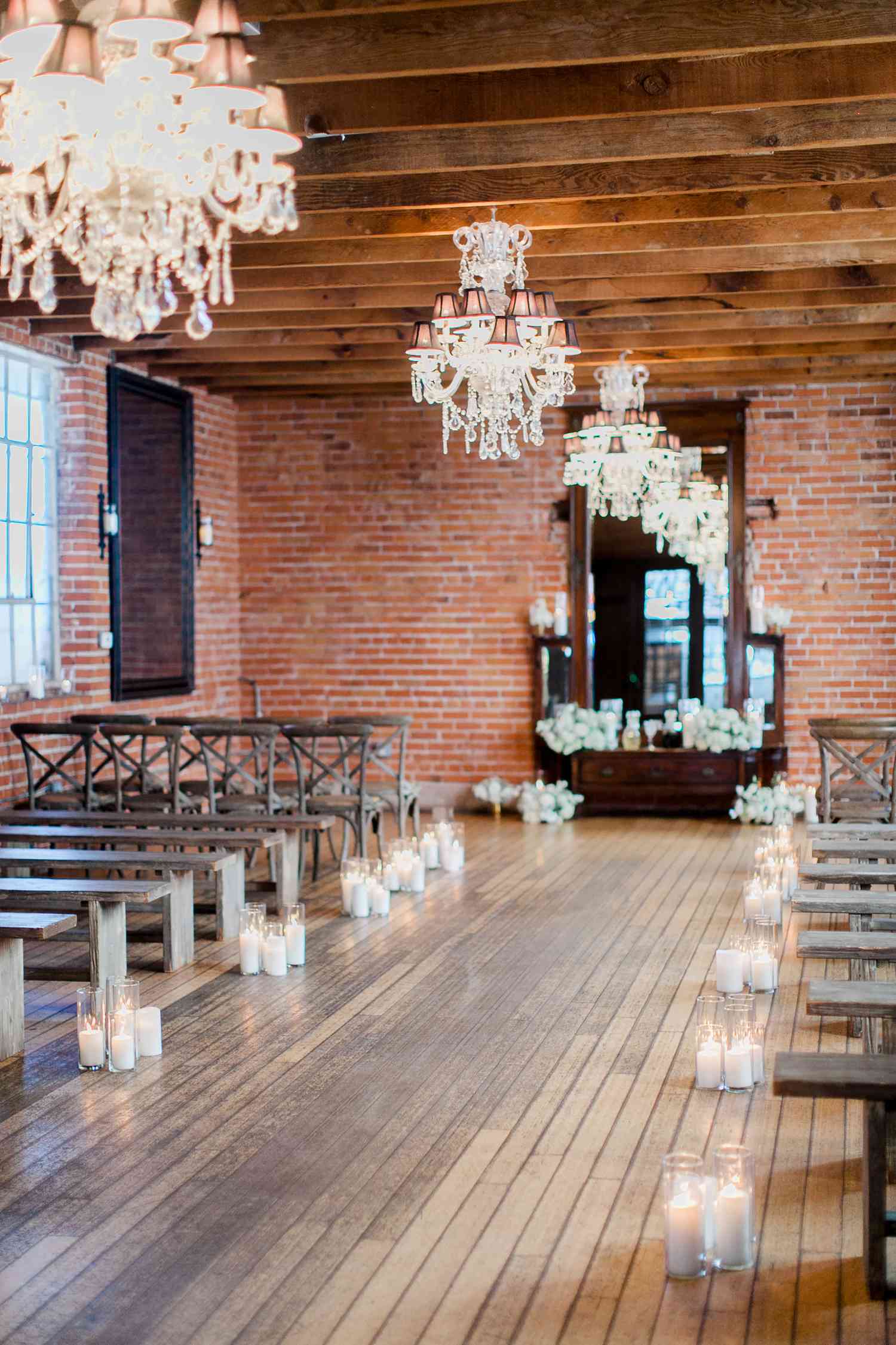 Candle-lined ceremony aisle with wooden floors and ceilings and red brick walls