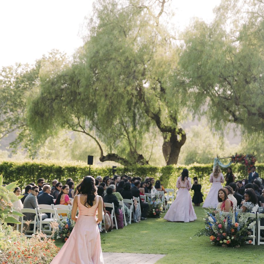Wedding party processional during ceremony at an outdoor wedding surrounded by lush trees