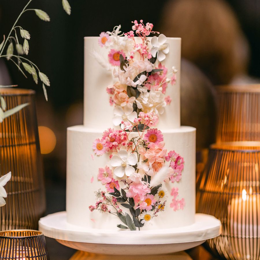 Two-tier white white wedding cake with pink and white pressed flowers in the middle