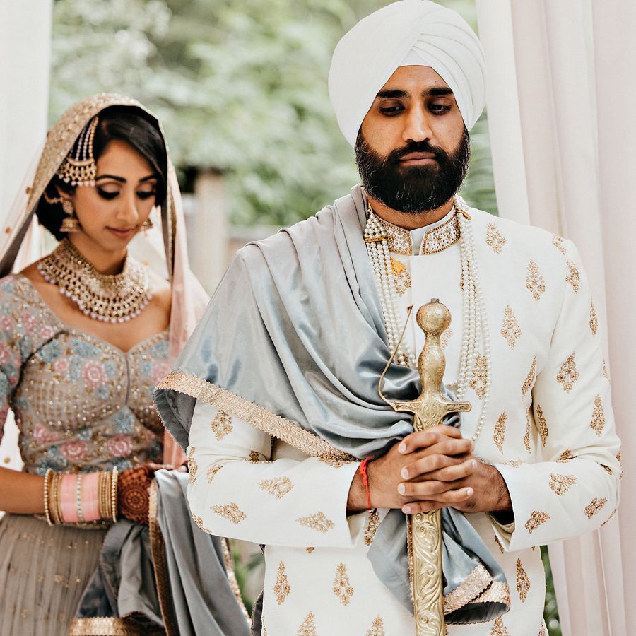 bride and groom posing in traditional clothing during a sikh wedding ceremony
