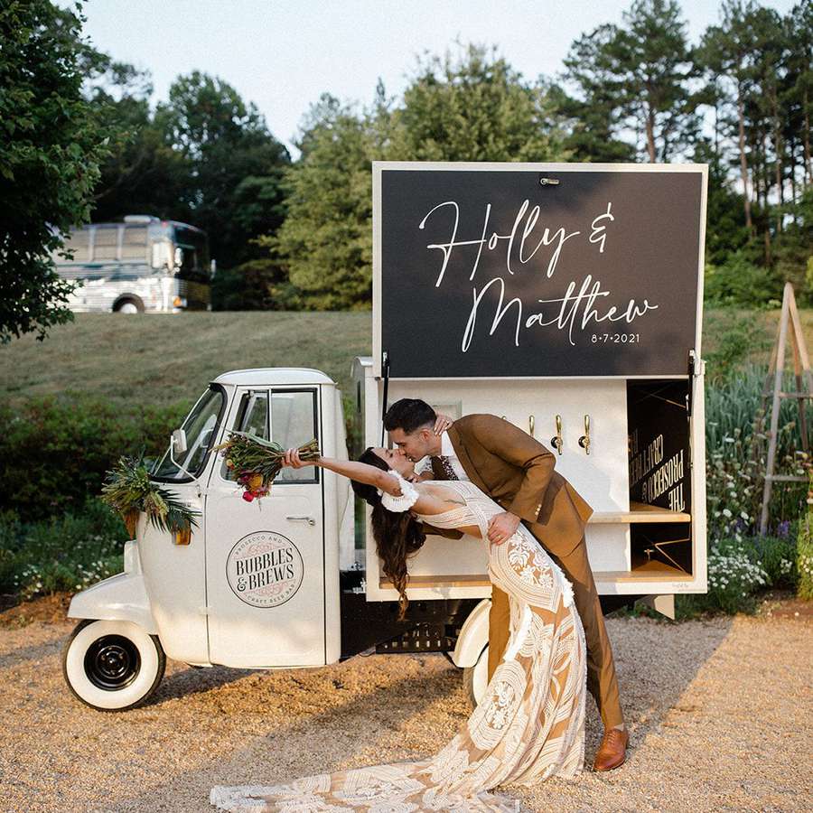 Holly and Matt kissing in front of their mobile bar cart