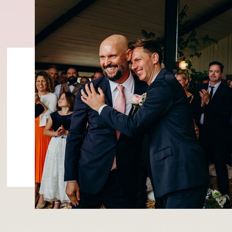 Grooms in navy suits exchanging rings during wedding ceremony