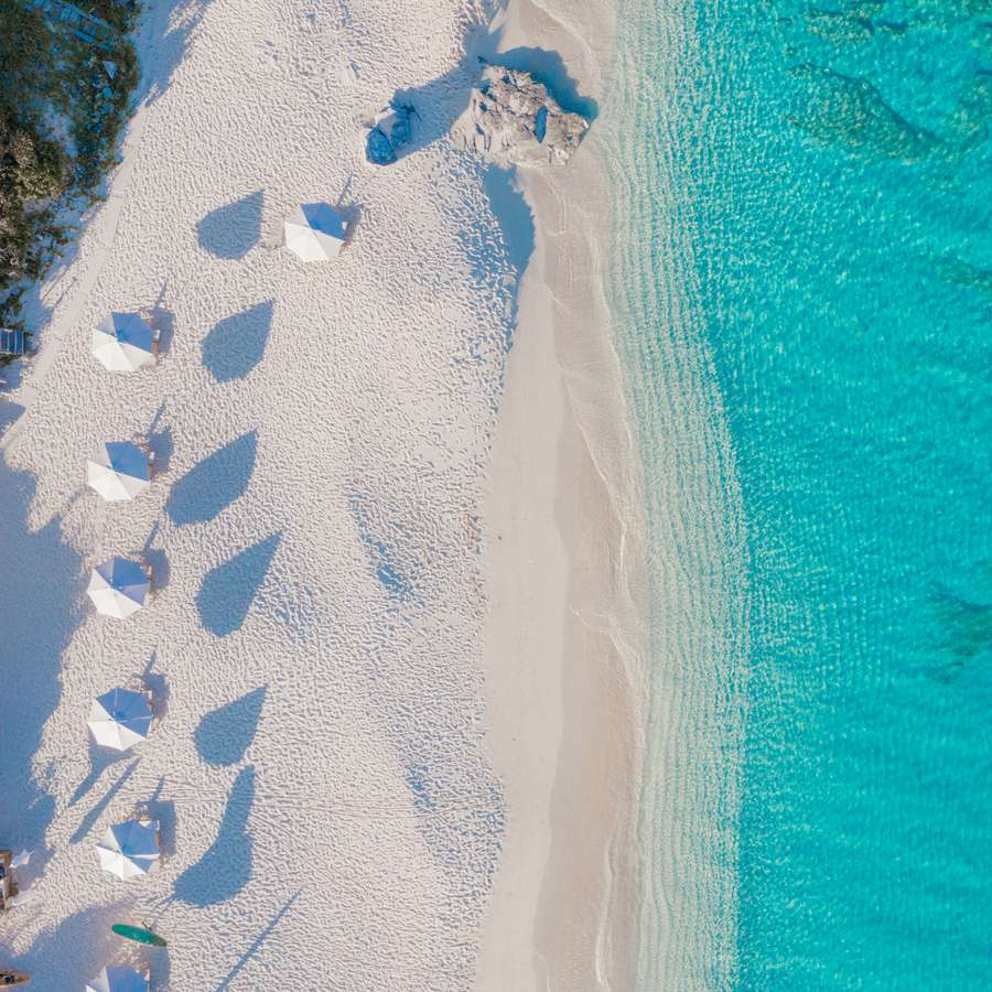 Turks & Caicos luxury honeymoon resort Amanyara with white sand beach, umbrellas, and turquoise water.