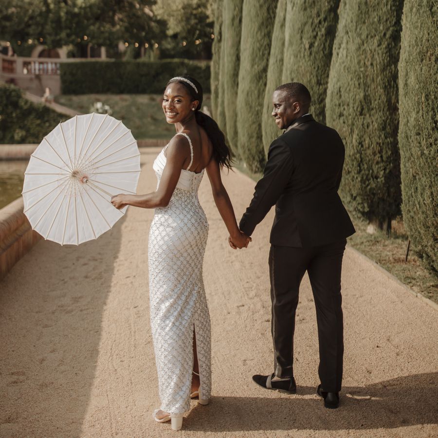 Bride Holding Parasol Walking with Groom at Tree-Lined Wedding Venue
