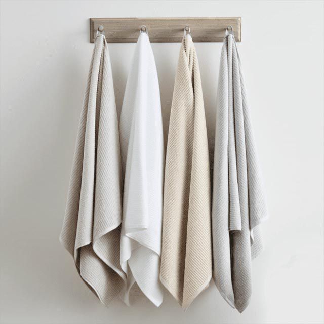 Neutral colored bath towels hanging from pegs
