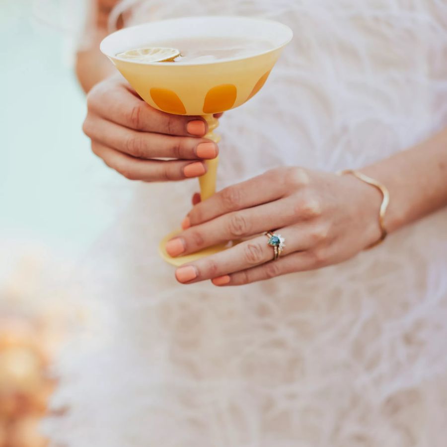 bride holding a yellow cocktail glass