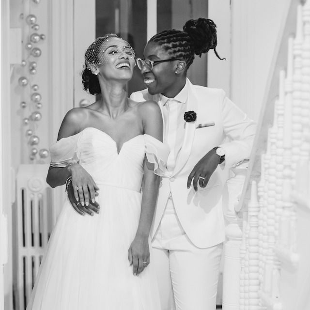 Newlyweds dressed in white laughing and enjoying a moment by the stairs
