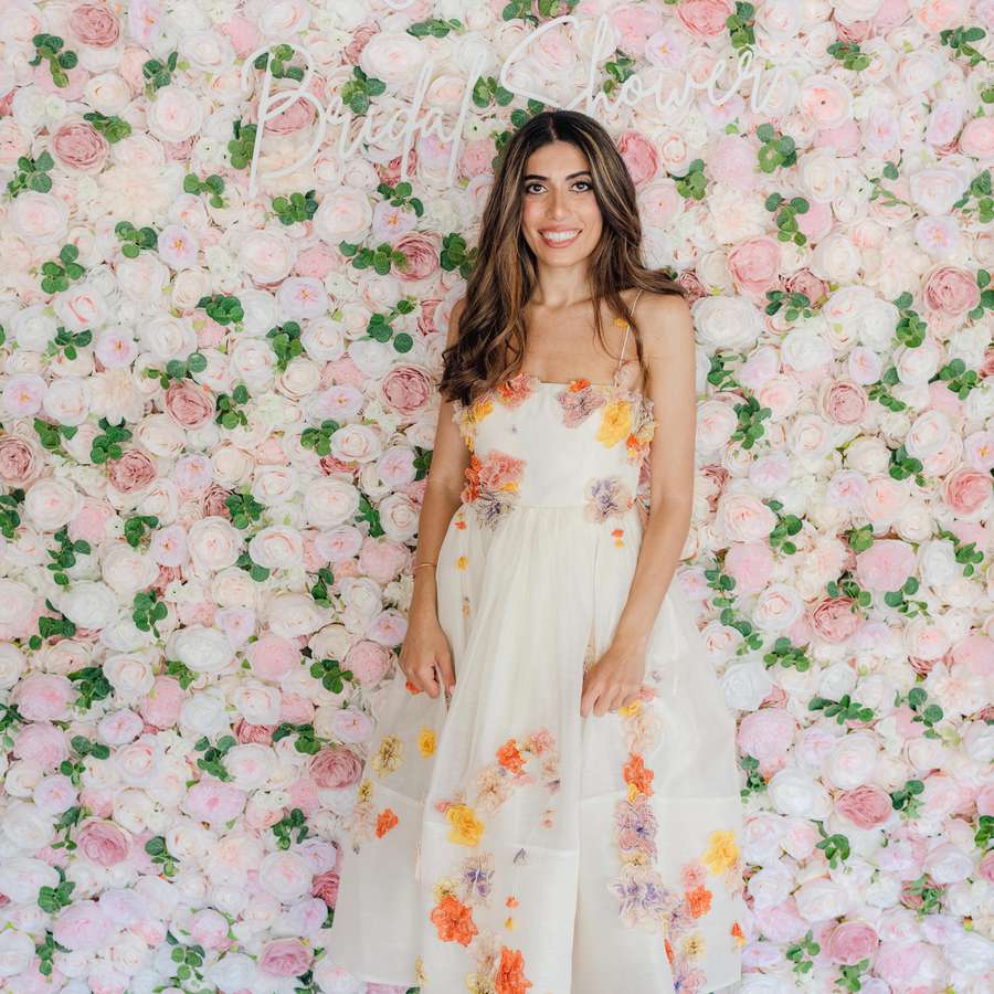 woman standing against a flower wall