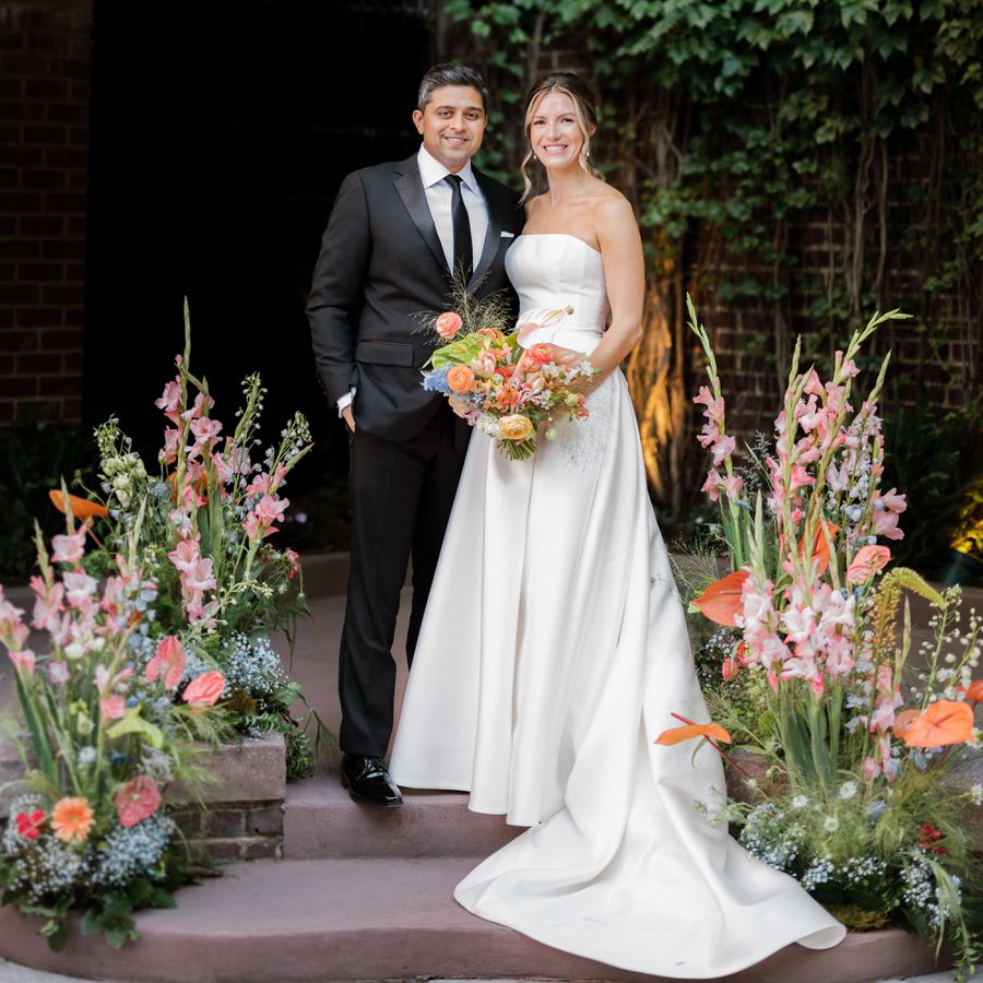 Bride and Groom Portrait with Colorful Floral Arrangements Behind Them