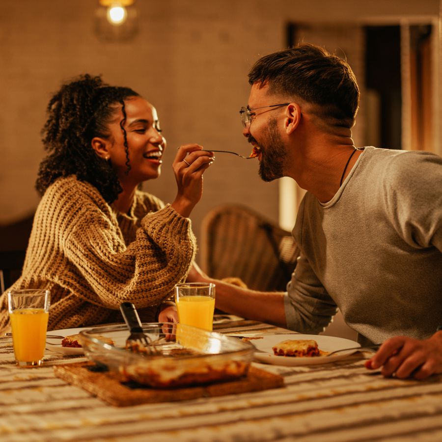 A young smiling couple having a romantic date night dinner at home with a homemade meal.