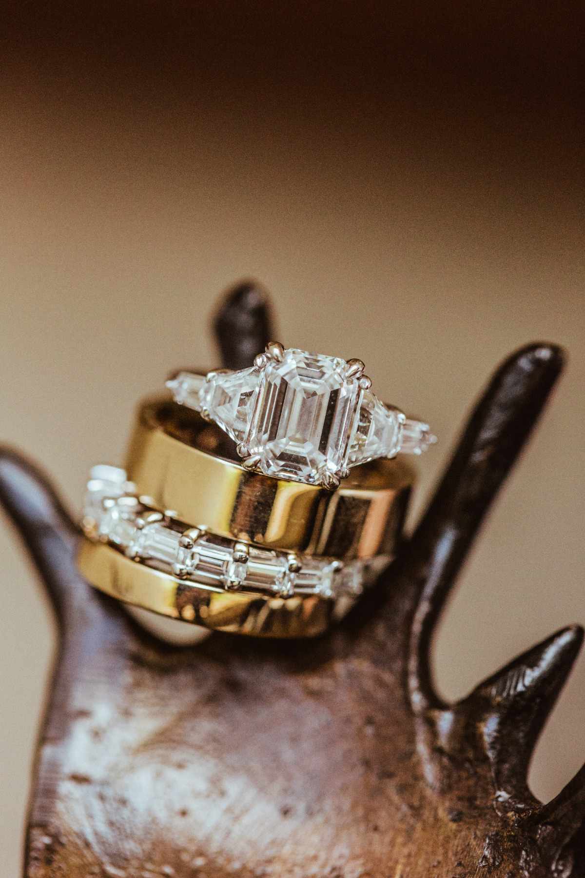 A diamond engagement ring and baguette diamond wedding band with two gold bands on ring holder