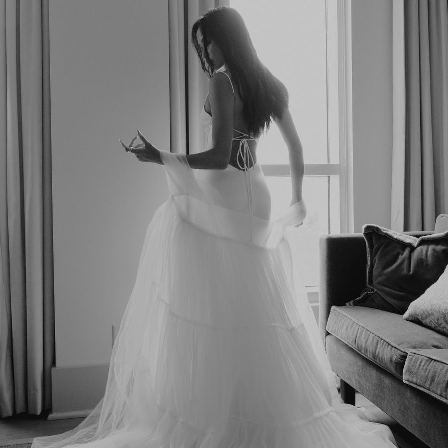 black and white photo of a bride putting on her wedding dress