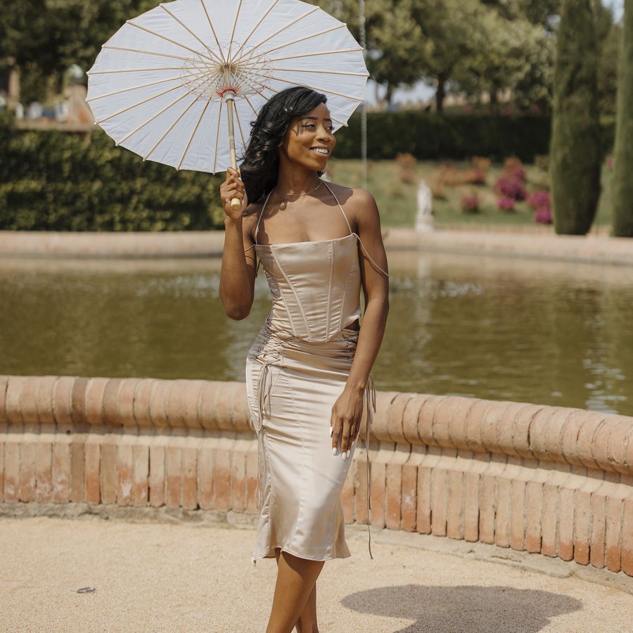 wedding guest wearing a two piece being cocktail dress holding a parasol
