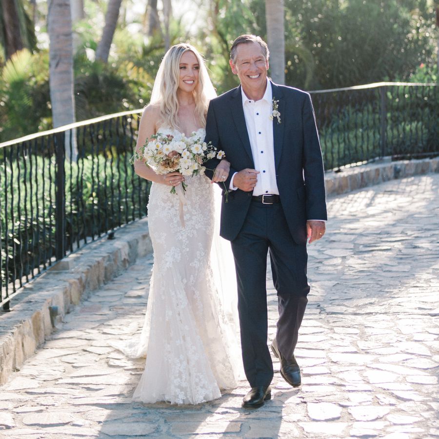father walking his daughter down a cobblestone wedding aisle