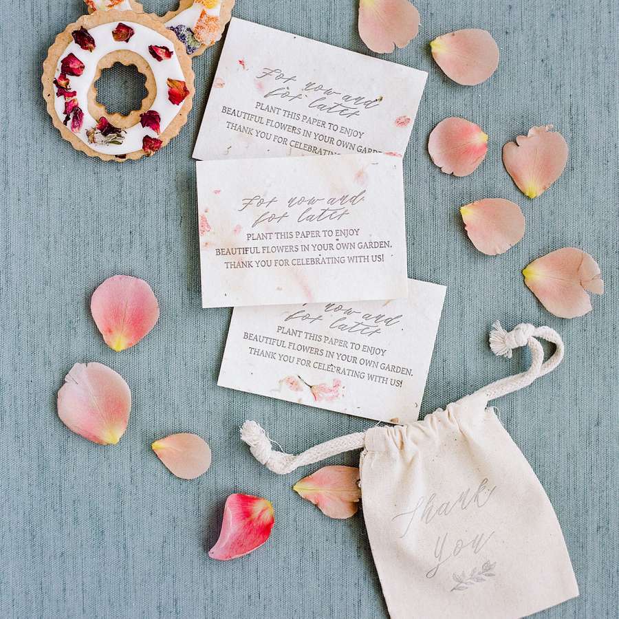 Flower seed paper wedding favors displayed on a blue surface with flower petals and cookies
