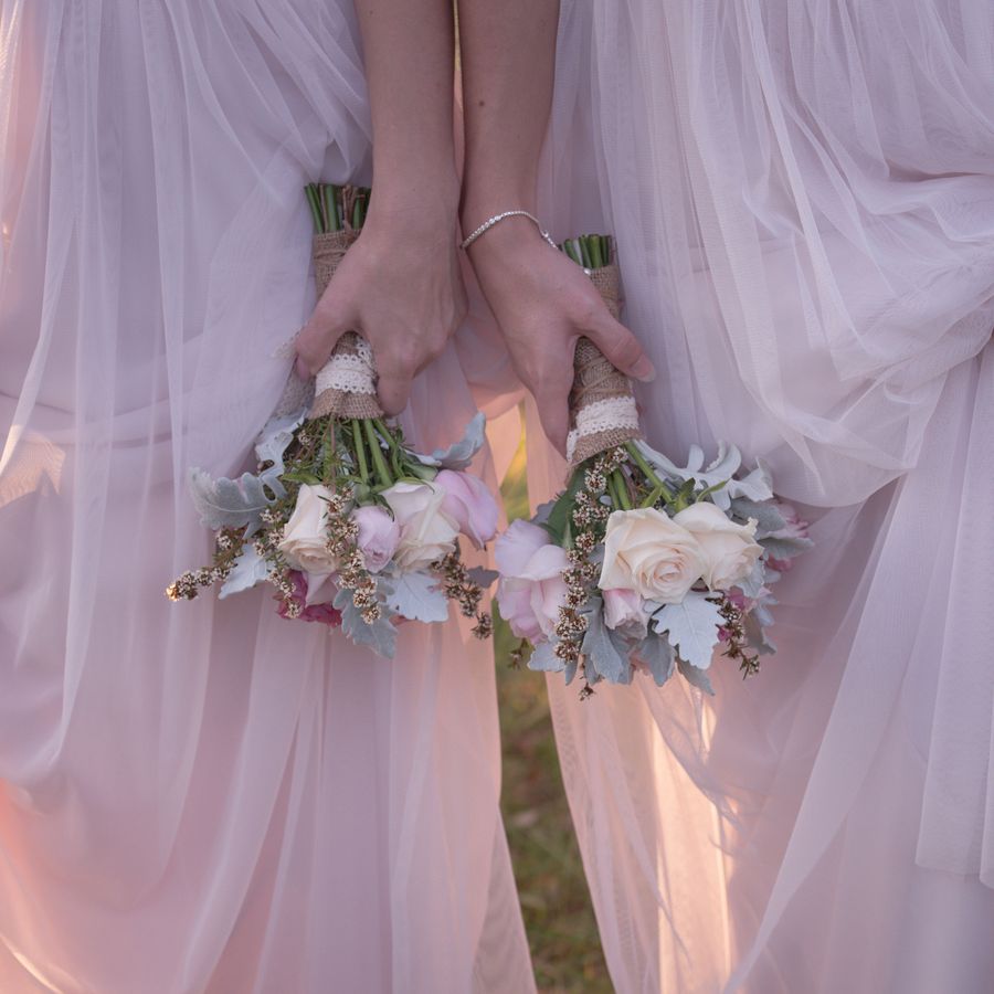 Two bridesmaids holding bridesmaid bouquets stand together at a wedding.