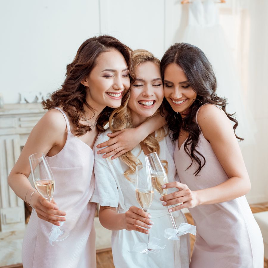 Bride with bridesmaids embracing and toasting