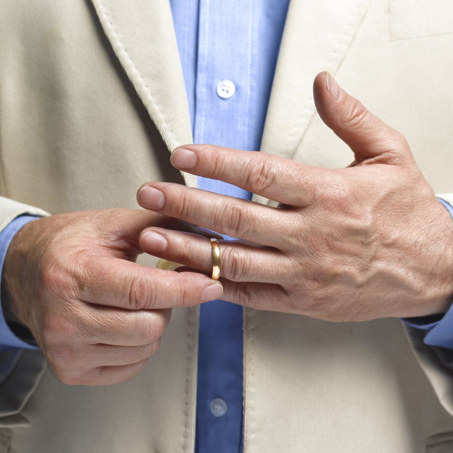 Man putting on a gold wedding band on his left ring finger
