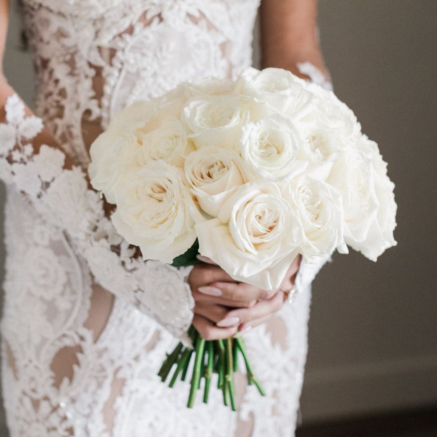 bride in lace dress holding bouquet of white roses