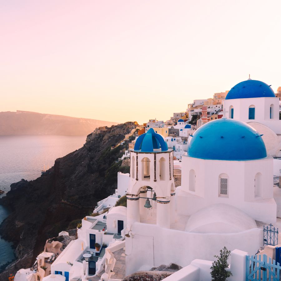A view of white-washed buildings with blue rooftops in Greece, a honeymoon destination.