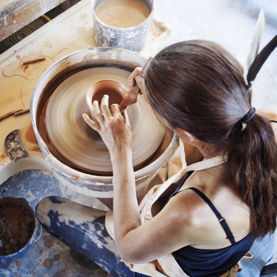 A woman making clay pottery using a kiln.