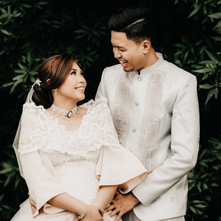 Filipino bride and groom in wedding wedding attire smiling at outdoor wedding ceremony.
