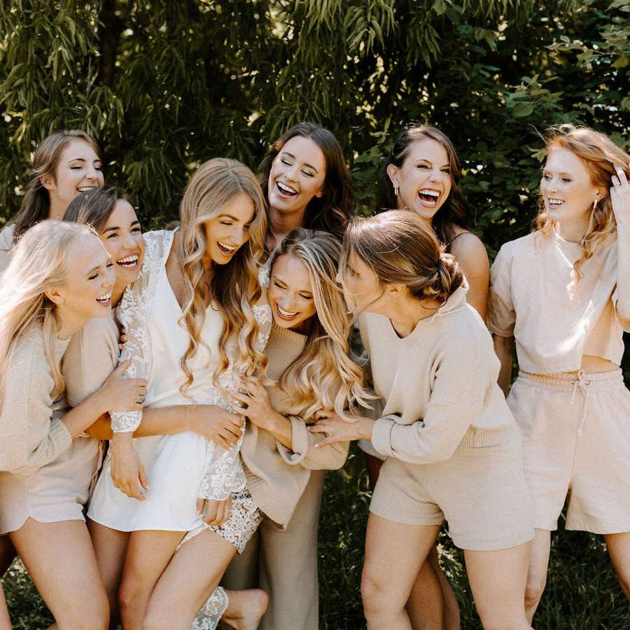bride and bridesmaids in matching nude pajama sets laughing