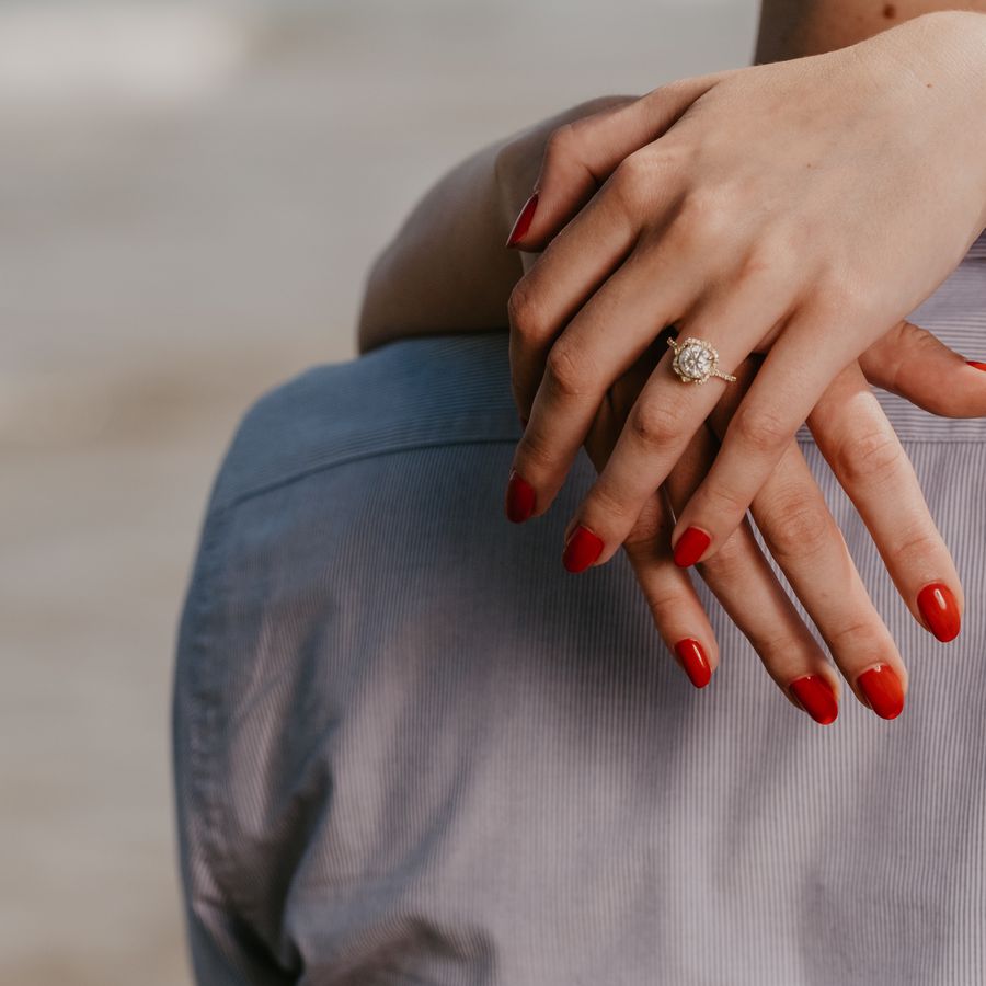 Woman with red nails and wearing an engagement ring