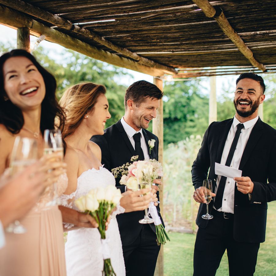 Wedding party laughing with bride and groom at outdoor wedding