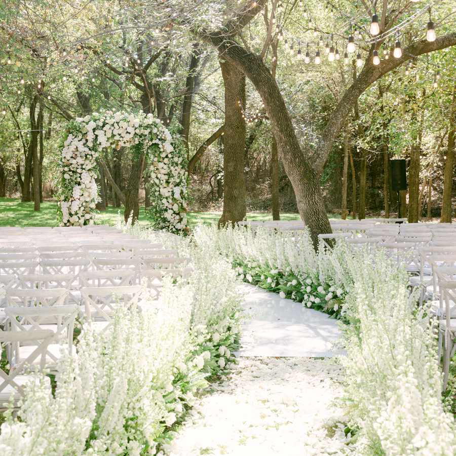 Outdoor Wedding Ceremony in Garden with Floral-Lined Aisle and Floral Arch