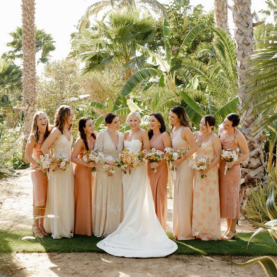 Bride and bridal party holding bouquets in front of palm trees