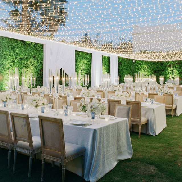 Dining tables and chairs set up for a wedding reception with string lights