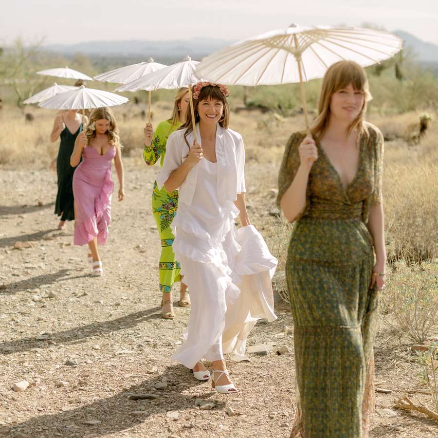 bride and bridesmaids walking in Arizona desert holding parasols instead of traditional bouquets