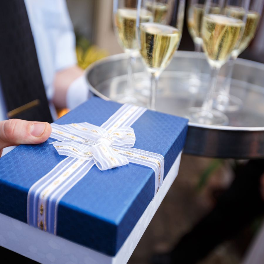 A guest holding an engagement party gift and champagne. 