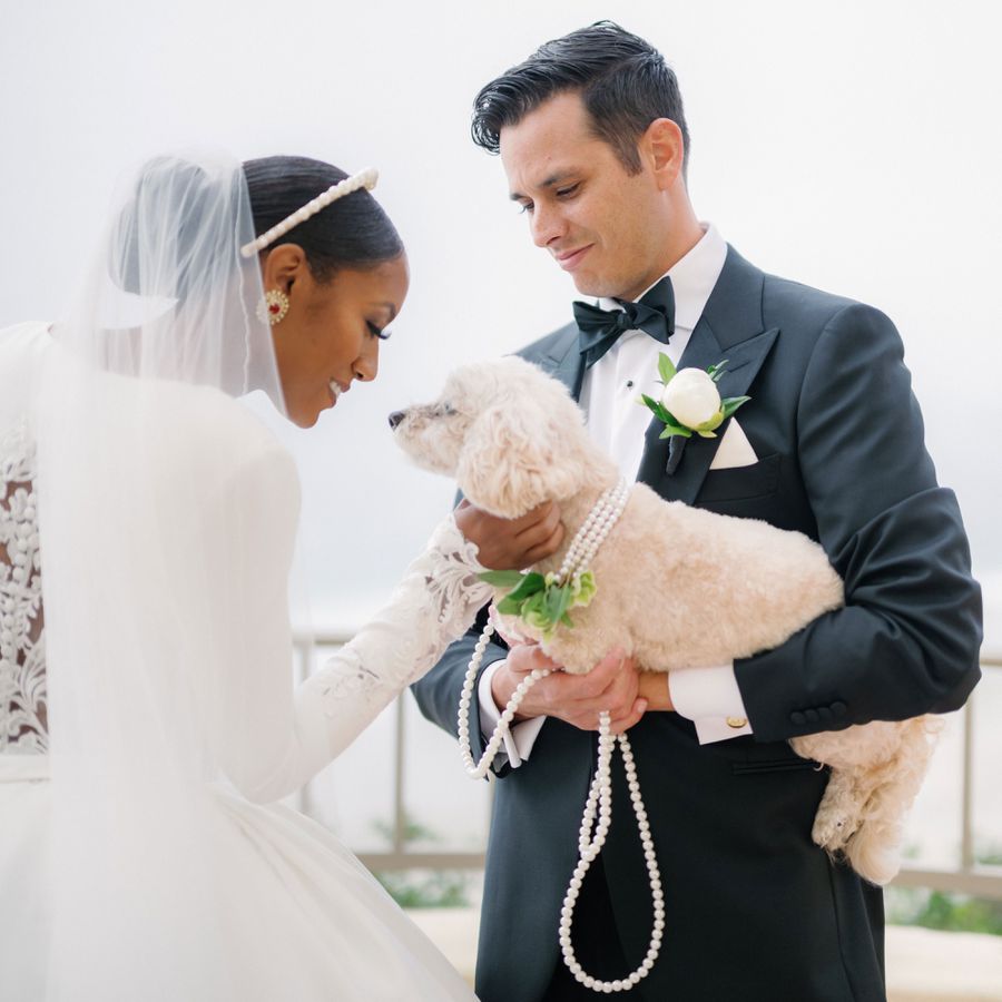 bride and groom with their dog in a pearl collar