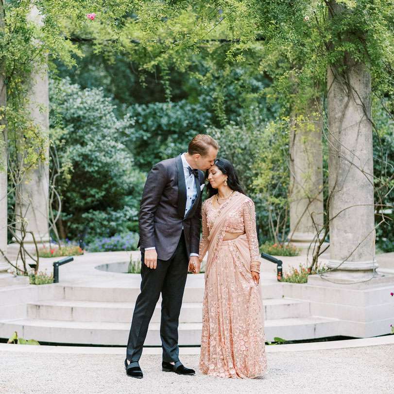 Rohini and Chad holding hands at their garden venue