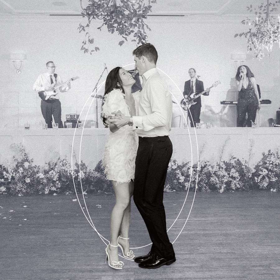 A newlywed couple dances in front of a live band at their wedding.