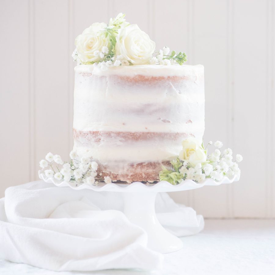 Single-Tier Semi-Naked Wedding Cake on White Stand Topped with Baby's Breath, Ranunculus, and Roses