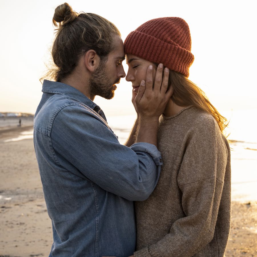 Romantic young man standing face to face with girlfriend at beach during sunset