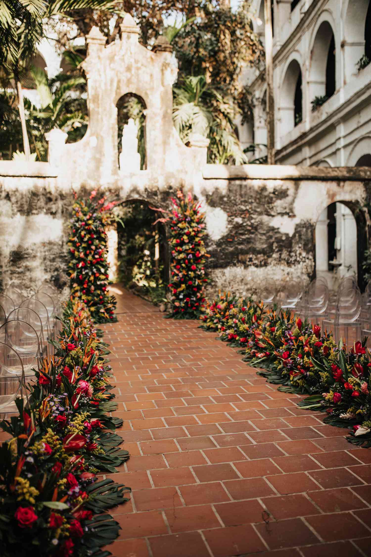 A wedding aisle with greens and pink flowers. 