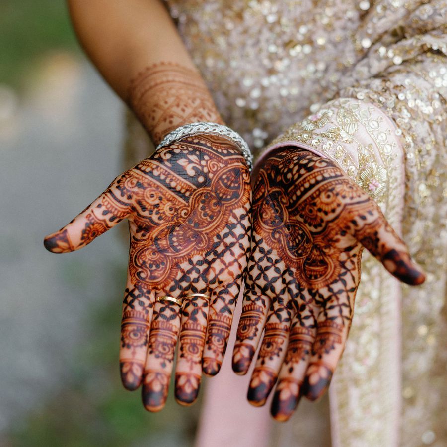 Bride's hands covered in black and orange henna designs