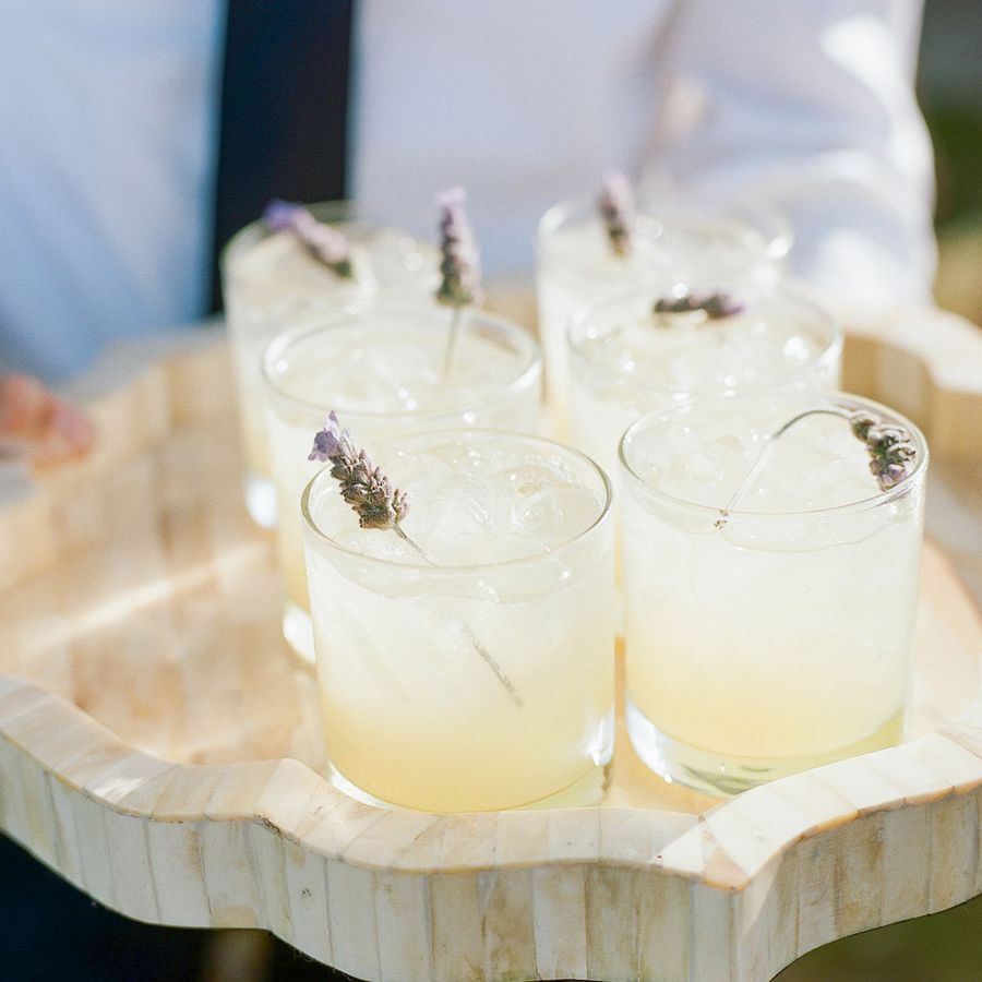 Waiter holding a wooden tray of lemonade with lavender sprig