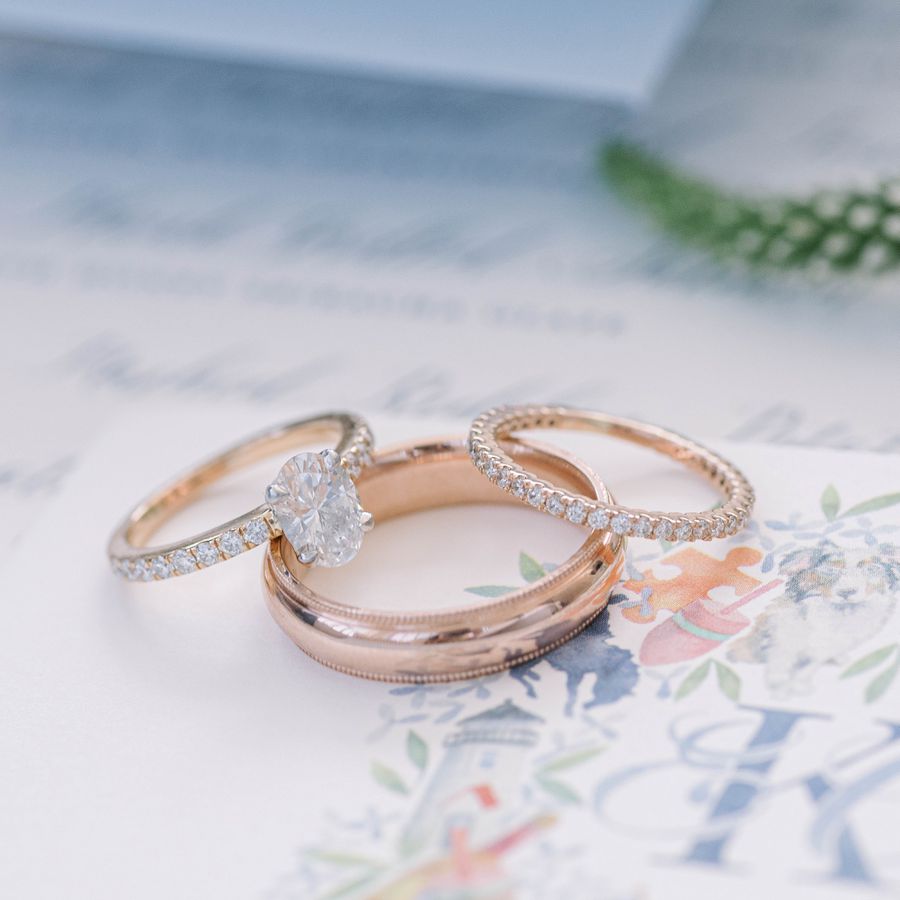 still shot of a gold diamond engagement ring, a pave diamond gold wedding band, and a plain gold wedding band