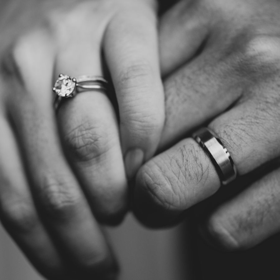black and white couple interlocking fingers showcasing their wedding rings