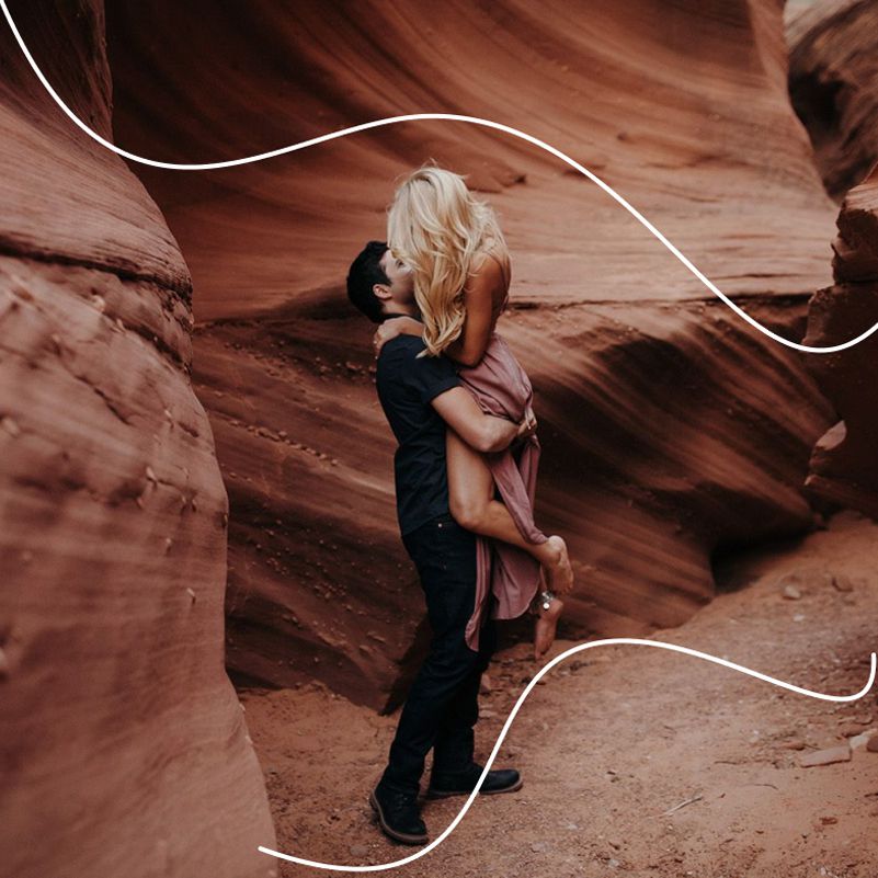 Engaged couple kissing in lifted embrace in canyon