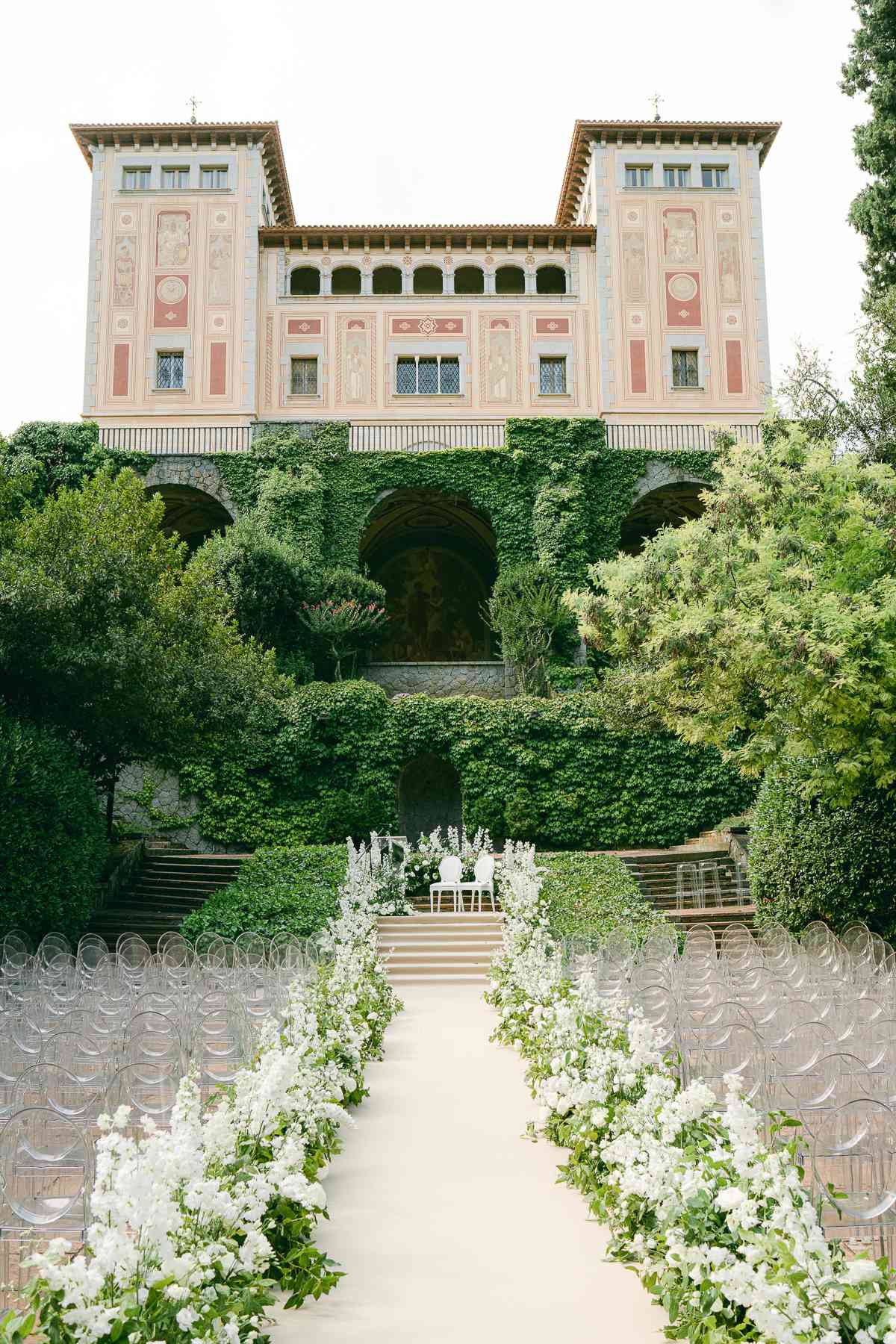 A wedding aisle decorated with white flowers and greenery. 