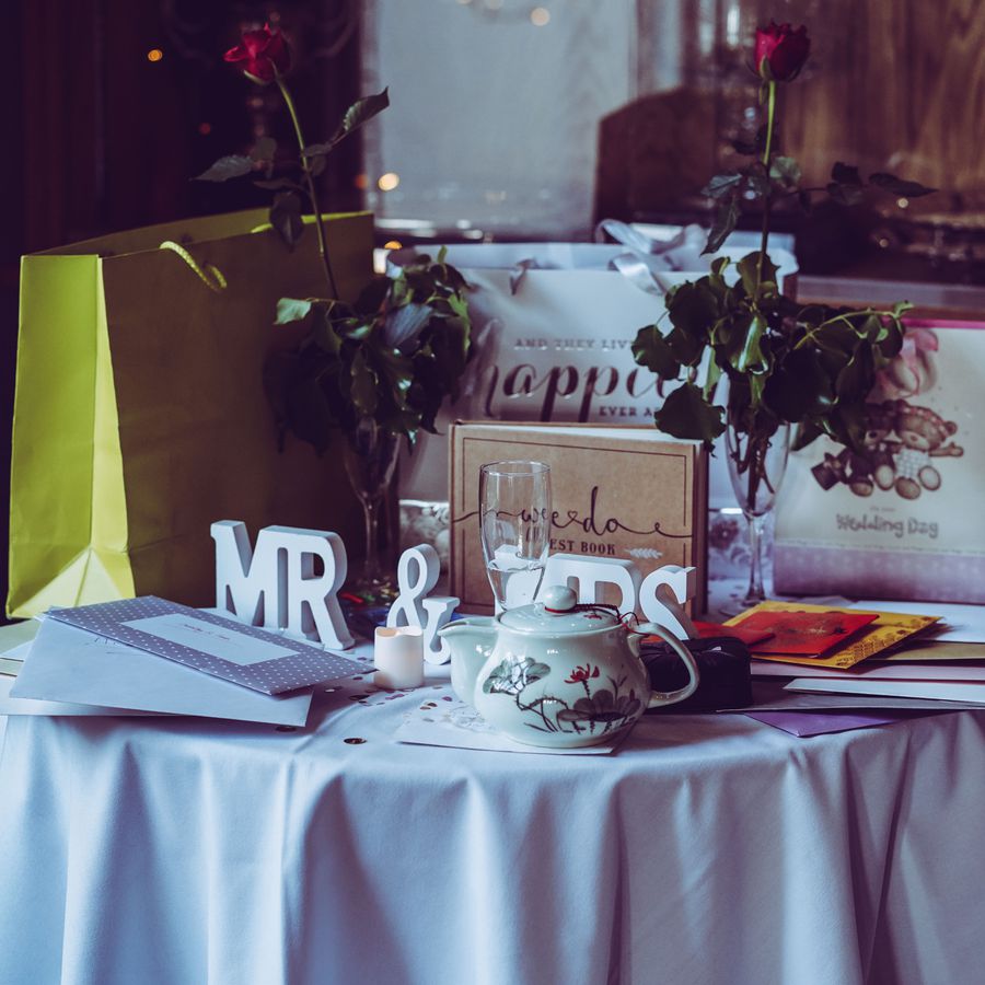 A wedding gift table with wrapped gifts and gift bags, red roses, wedding cards, and a Mr. and Mrs. sign